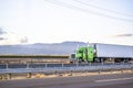 Bright green classic big rig semi truck tractor transporting cargo in refrigerator semi trailer driving on the flat road in Royalty Free Stock Photo