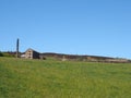 Bright green grass meadow covered in on a hillside with the old mill chimney and stone house houses at old town near hebden Royalty Free Stock Photo