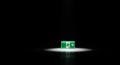 Green illuminated emergency exit sign with running man symbol spotlighted in darkness Royalty Free Stock Photo