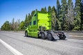 Bright green powerful big rig semi truck tractor without the semi trailer running on the wide highway road to warehouse for pick Royalty Free Stock Photo
