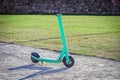 Bright green scooter standing in the middle of a road near green lawn on sunny summer day