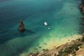 Bright green sea near the rocky shore, on which a white yacht floats Royalty Free Stock Photo