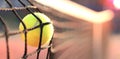 Bright greenish yellow tennis ball hitting the net