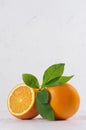 Bright group oranges with fresh green leaf and piece on soft light white modern background, vertical.