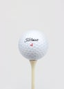 A bright, high-key portrait of a Titleist golf ball on a golf tee.