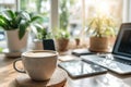 Bright home workspace featuring a laptop, smartphone, coffee cup, and a potted plant, bathed in natural sunlight by the window Royalty Free Stock Photo