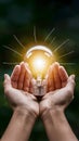Bright idea depicted by shining lightbulb cradled in human palms, concept of innovation