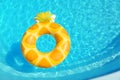 Bright inflatable pineapple ring floating in swimming pool on sunny day, above view Royalty Free Stock Photo