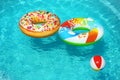 Bright inflatable  and beach ball floating in swimming pool on sunny day. Space for text Royalty Free Stock Photo