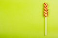 Bright juicy colored lollipop on a green background. Lollipop in the form of a color spiral.