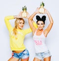 Bright juicy portrait of two cheerful girlfriends, having fun with slice pineapple and smiling. Casual style, bright