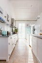 Kitchen interior with modern white furniture, pastel mint fridge and big floor to ceiling window