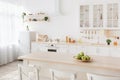 Bright kitchen interior. White furniture and shelves with utensils and plates, small refrigerator near window Royalty Free Stock Photo