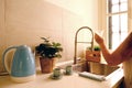 bright kitchen, woman gathering clean water into glass for drinking from modern chrome faucet, concept of thirst, health, take Royalty Free Stock Photo