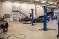 In a bright large car workshop there are lifting platforms and a car