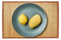 Bright lemon and yellow mango on a gray plate on a cane tablecloth