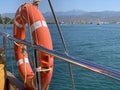 A bright lifebuoy on board the yacht. Railings of a sea ship against the background of the sea and mountains. A circle for