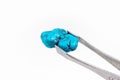 Bright light blue Turquoise crystal gem in the pincers on light background close up with copy space. Royalty Free Stock Photo