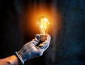 Bright light bulb held by gloved hand in a dim environment during evening hours Royalty Free Stock Photo