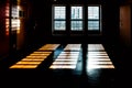 Bright light enters through windows and casts dark shadows on the floor. Bars are visible in front of the windows, just like in a