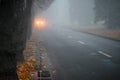 The bright light of the headlights of the car. City street with cars in the distance is in poor visibility. Heavy fog on the road Royalty Free Stock Photo