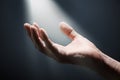 Bright light rays shihing on man`s hand in darkness. Royalty Free Stock Photo