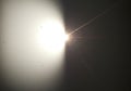 A bright light source creates a lens flare on a surface, with visible rays of light Royalty Free Stock Photo