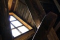 Bright light from the window falls on beams and cobwebs in an old wooden house