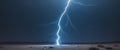 Bright lightning bolt touching down on open desert landscape at night with dark sky Royalty Free Stock Photo