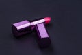 Bright lipstick in purple tube on black background.