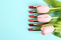 Bright lipsticks and spring flowers on light blue background. Space for text