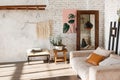 Bright loft interior with white brick walls, mirror, modern light, sofa, decor.