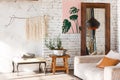 Bright loft interior with white brick walls, mirror, modern light, sofa, decor.