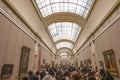 Louvre museum longest room with the walls full of paintings with a fully packed of visitor