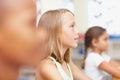 The bright minds of tomorrow in training. Young girl in amongst classmates, looking up attentively in class - copyspace.