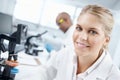 Bright minds at work. Closeup portrait of a gorgeous female scientist in front of a microscope with a male colleague in