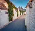 Bright morning view of empty strret with trullo trulli - traditional Apulian dry stone hut with a conical roof