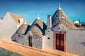 Bright morning view of strret with traditional Apulian dry stone hut with a conical roof