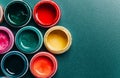 Bright, mother-of-pearl, multicolored open cans of paint on a blue background. View from above.