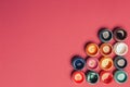 Bright, mother-of-pearl, multicolored open cans of paint on a bright pink background. View from above.