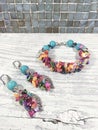 Bright multi-colored bracelet and earrings on a light table.