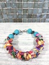 Bright multi-colored bracelet made of natural stones on a light wooden table.