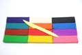 Bright multi-colored plasticine sticks and sculptural knife on white background