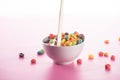 Bright multicolored breakfast cereal in bowl with pouring milk Royalty Free Stock Photo