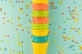 Bright multicolored ice-cream waffle cones on blue background with scattered confetti sugar sprinkles Royalty Free Stock Photo