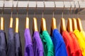 Bright multicolored T-shirts hang on wooden hangers in the store
