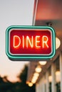 Neon diner sign glowing brightly at twilight, showcasing retro design with vibrant colors, inviting atmosphere, and Royalty Free Stock Photo