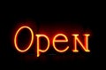 Bright neon orange letters OPEN flash on a black canvas, creating an atmosphere of mystery and at the same time being a