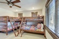 Bright new bedroom with two bunk beds with colorful bedding and ceiling fan