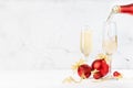Bright New Year background with with flow of pouring sparkling champagne from bottle to two glasses, shine christmas decoration.